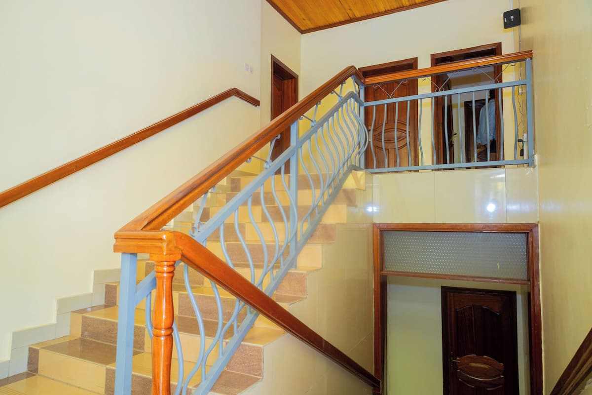 A staircase with wooden handrails and blue metal balusters, leading to an upper floor.