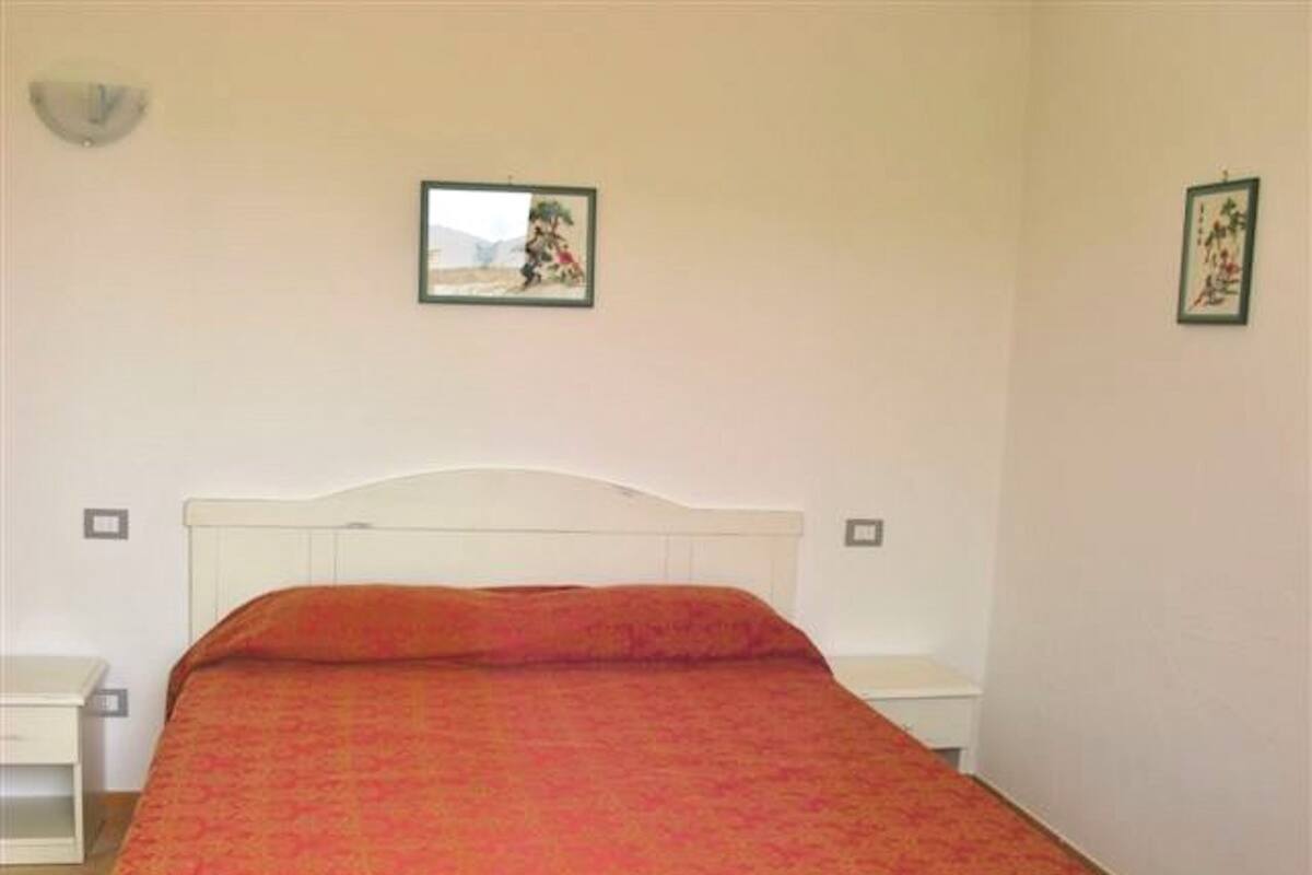 A bedroom with a single bed, white headboard, and two bedside tables.