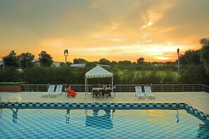 A pool area with lounge chairs and a gazebo. - The Devgarh Resorts (Vallabhnagar)