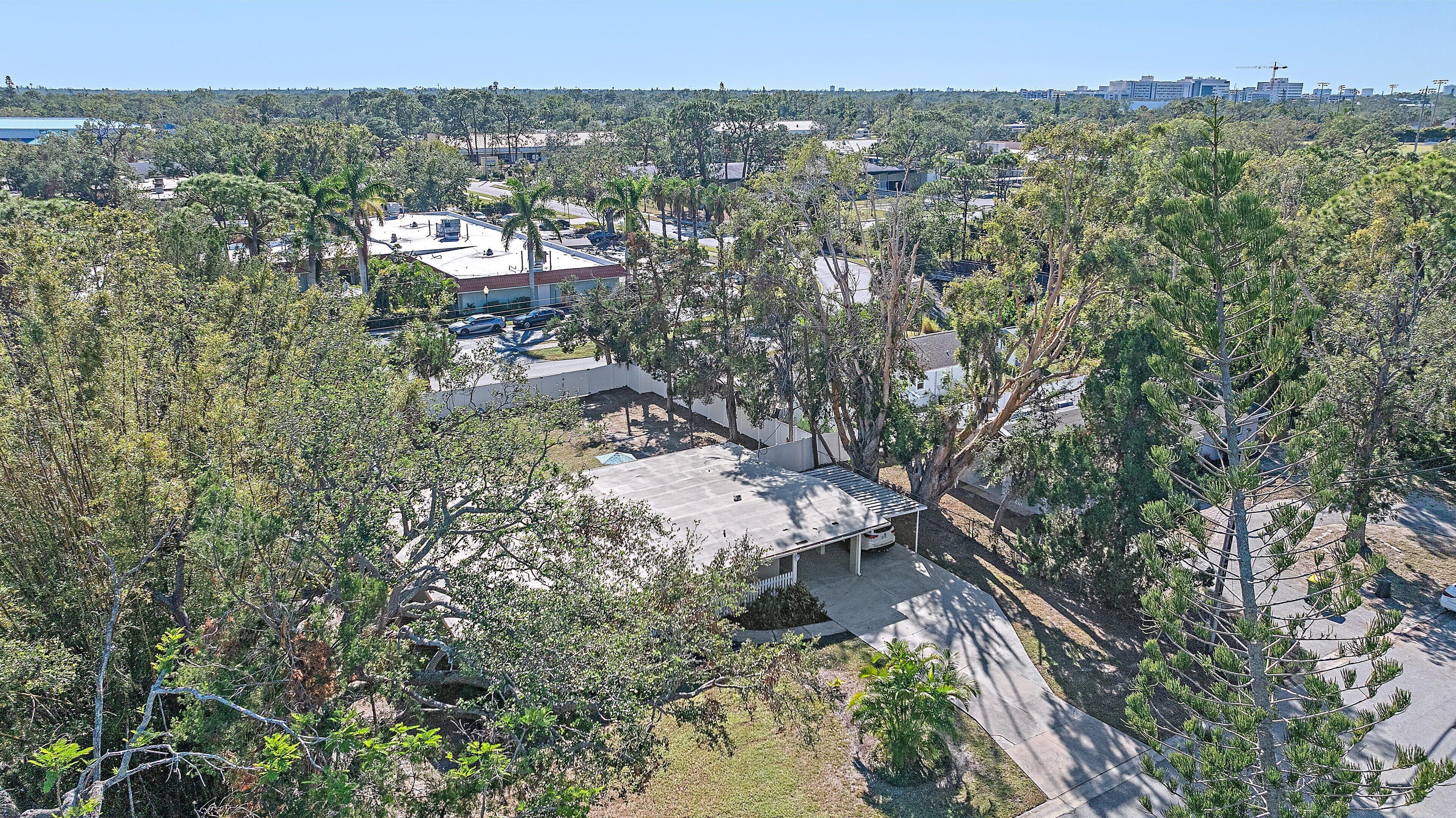 Vista aérea de uma área residencial com casas, árvores e céu claro.