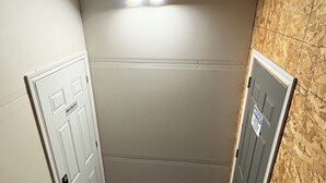 A small, enclosed room with a black carpet, two white doors, and a wooden wall. - 2 Bedroom 1 bathroom Man cave (Grande Prairie)