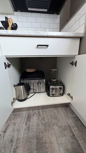 A compact kitchen with white cabinets, a built-in toaster, a kettle, and a blender. - 2 Bedroom 1 bathroom Man cave (Grande Prairie)