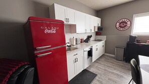 A compact kitchen with white cabinets, a red refrigerator, and a coffee machine. - 2 Bedroom 1 bathroom Man cave (Grande Prairie)