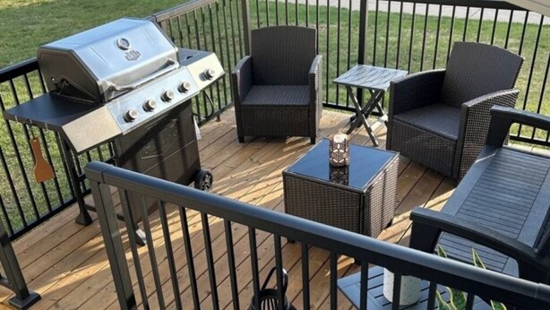 Una terrazza con mobili da esterno, un barbecue e vista su una strada residenziale.