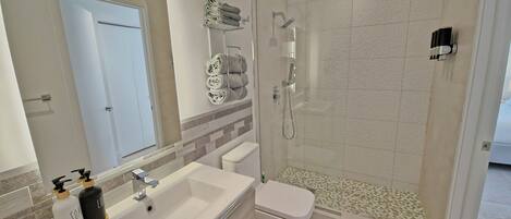 A modern bathroom with a sink, toilet, and shower.
