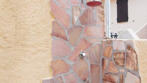 Pared de piedra con ducha y grifo de metal.