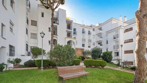 A courtyard with a bench, neatly trimmed hedges, and a building with balconies. - REF 96 - Charming Apartment with Pool Near Beaches & Golf Courses (Mijas)