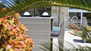 A wicker outdoor seating area with a poolside view, including a chair and a table with a white object on it. - San Pawl bnb Farmhouse Calypso (Xaghra)