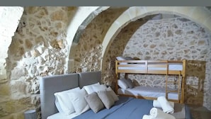 A bedroom with a stone wall, a bunk bed, a bedside table, and a lamp. - San Pawl bnb Farmhouse Calypso (Xaghra)