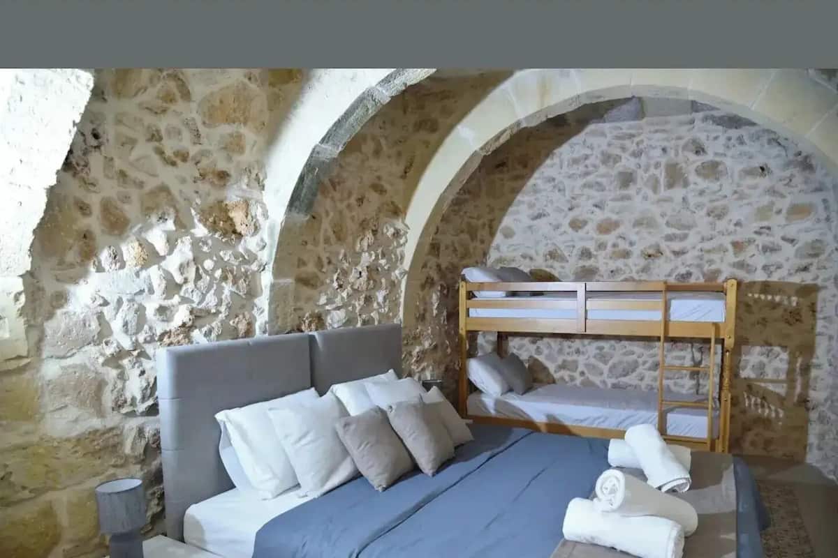 Una camera da letto con parete in pietra, un letto a castello, un comodino e una lampada.