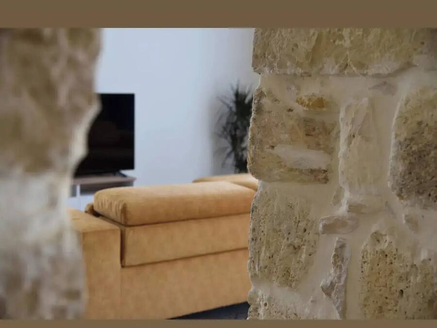 A room with a stone wall, a brown sofa, and a television in the background.