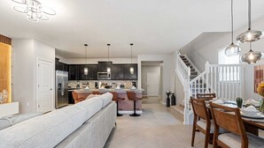 A modern kitchen with dark cabinets, a central island, and pendant lighting. - Brand New, Stylish Home 5B/4, 5B, Heated Pool & BBQ (Clermont)