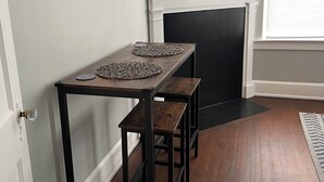 A dining area with a table and benches, a fireplace, and a wall-mounted clock.