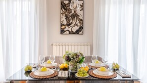 Ett matbord dukat med tallrikar, glas och frukt, omgivet av stolar och en vas med blommor.
