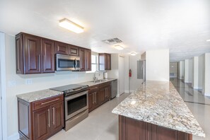 Eine moderne Küche mit Granit Arbeitsplatten, Edelstahlgeräten und Holzschränken.