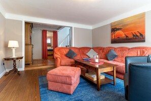 Un salon comprenant un canapé, une table basse, une lampe et un tableau accroché au mur.