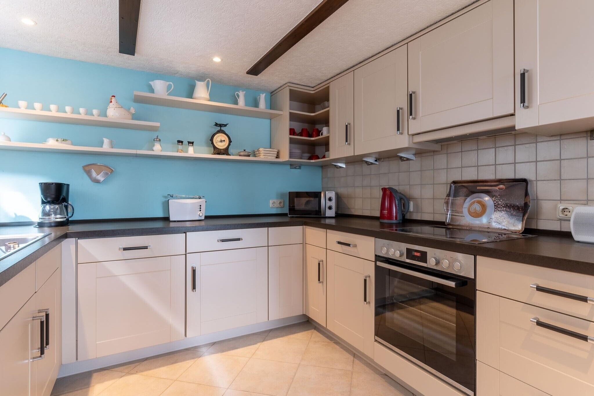 A modern kitchen with white cabinets, a microwave, an oven, and a coffee maker.