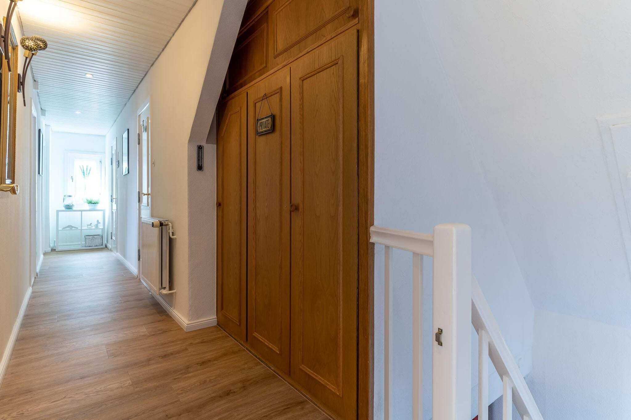A hallway with wooden flooring, a white railing, and a door labeled 'PRIVATE.'