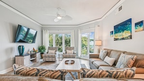 A spacious living room with a ceiling fan, a flat-screen TV, a sofa set, and a coffee table. - Ocean Front Villa w/ Private 4th Floor Balcony (Hilton Head Island)