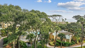 A resort with a pool area, palm trees, and a view of the ocean. - Ocean Front Villa w/ Private 4th Floor Balcony (Hilton Head Island)
