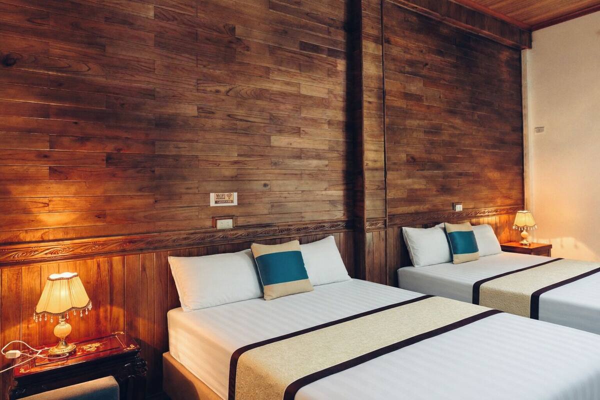 Une chambre d’hôtel avec deux lits, des lambris en bois sur les murs, des lampes de chevet et un panneau au-dessus des lits.