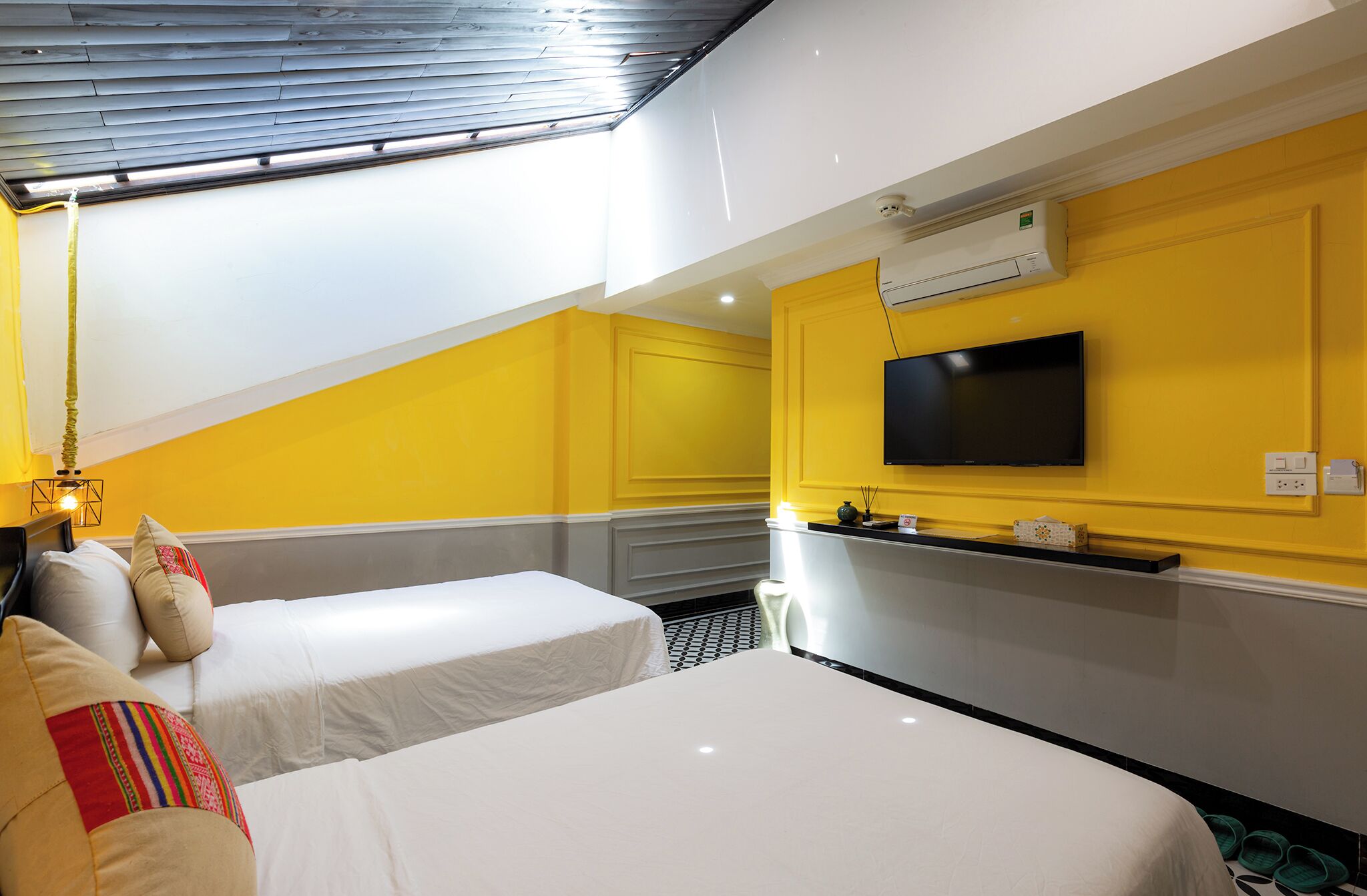 A hotel room with two beds, a TV, and an air conditioning unit.