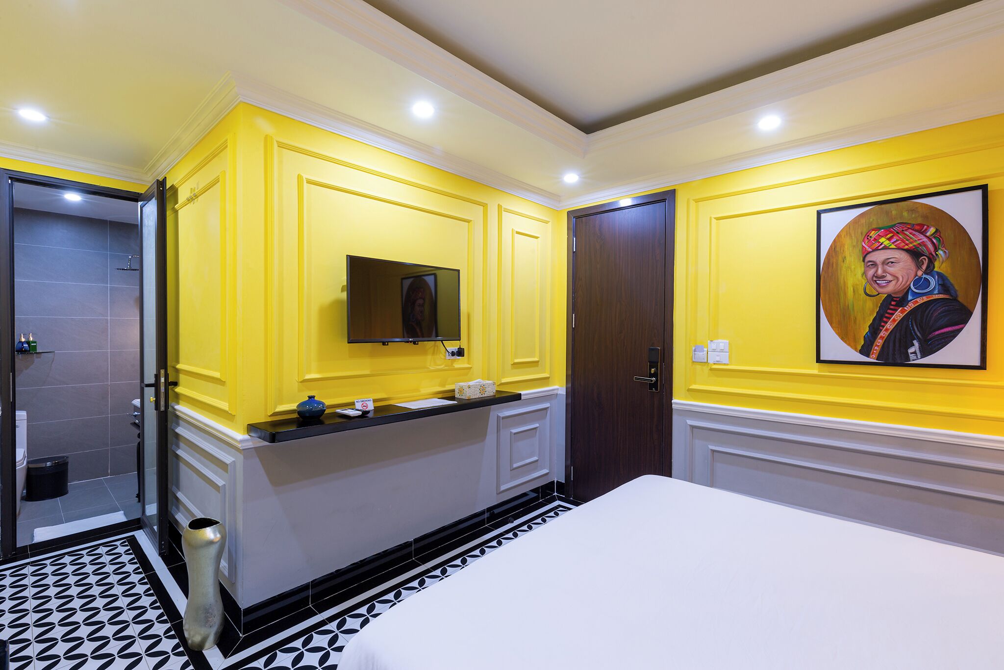 Habitación de hotel con pared de acento amarilla, una cama grande, una tocador con espejo y un cuadro en la pared.