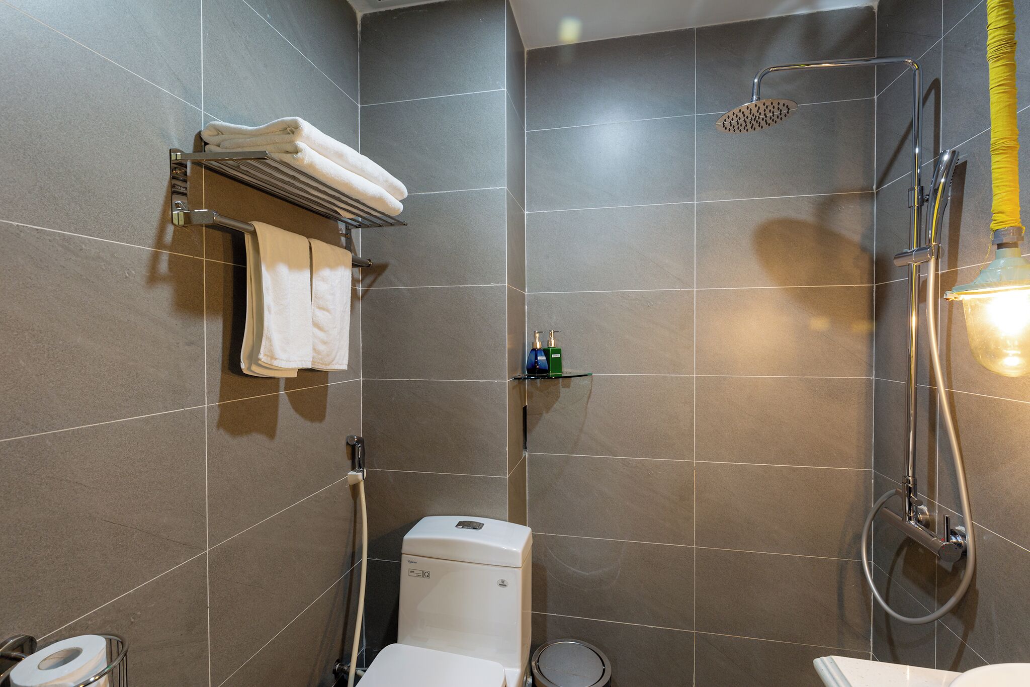 A modern bathroom with a shower, toilet, and towel rack.