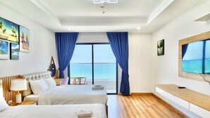 Een hotelkamer met twee bedden, een televisie, een balkon met uitzicht en een houten vloer.