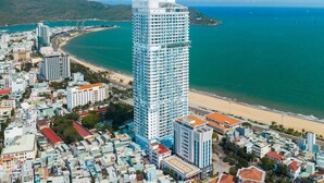Een kuststadsgezicht met een opvallend hoog hotel, modern van design, vlakbij een strand en omringd door andere gebouwen.