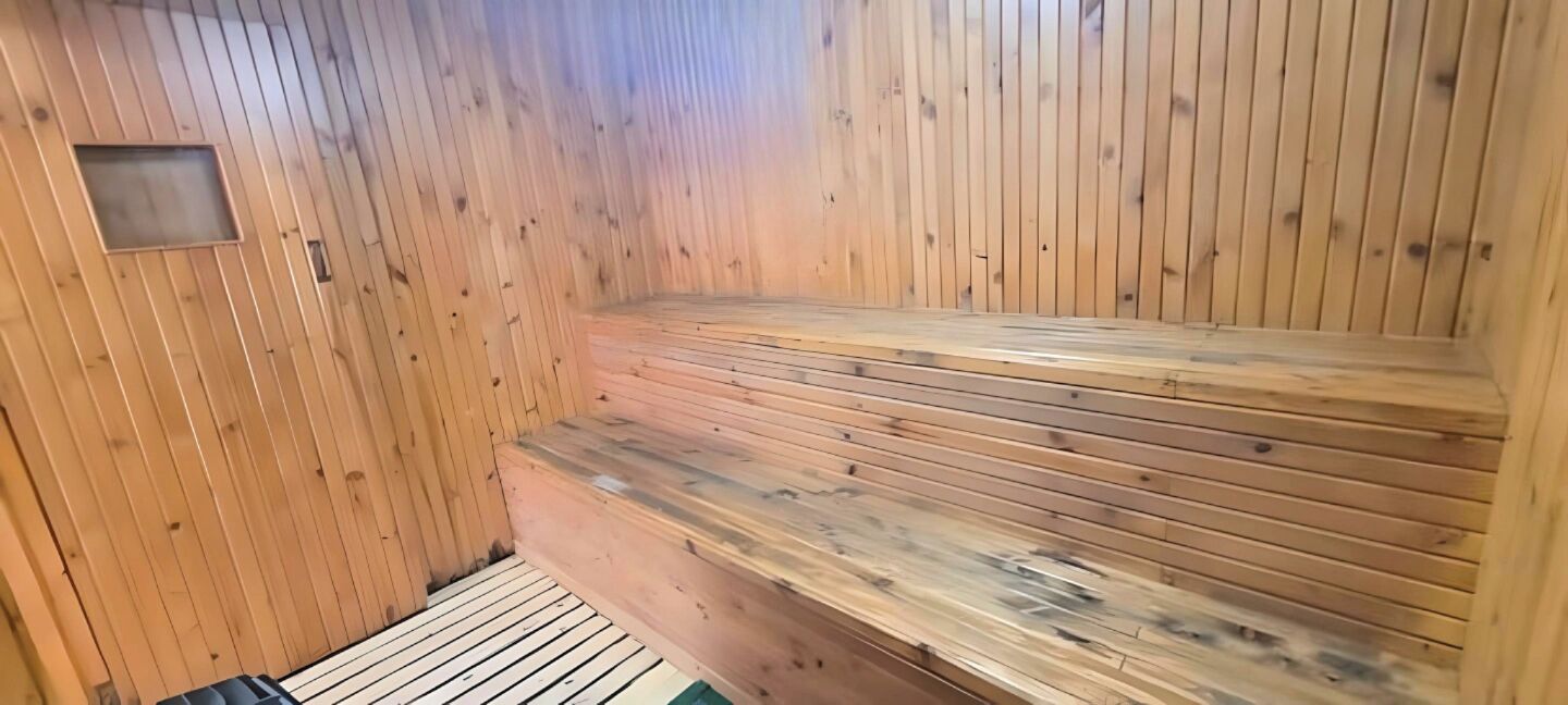 Un sauna avec des bancs en bois et un plancher incliné.