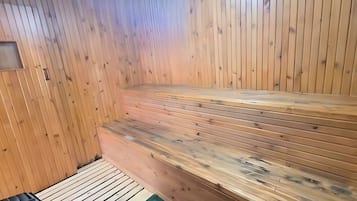 Un sauna avec des bancs en bois et un plancher incliné.