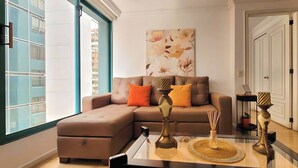 A modern living room with a sectional sofa, a glass coffee table, and a decorative vase. - Fontana Suites (Quito)