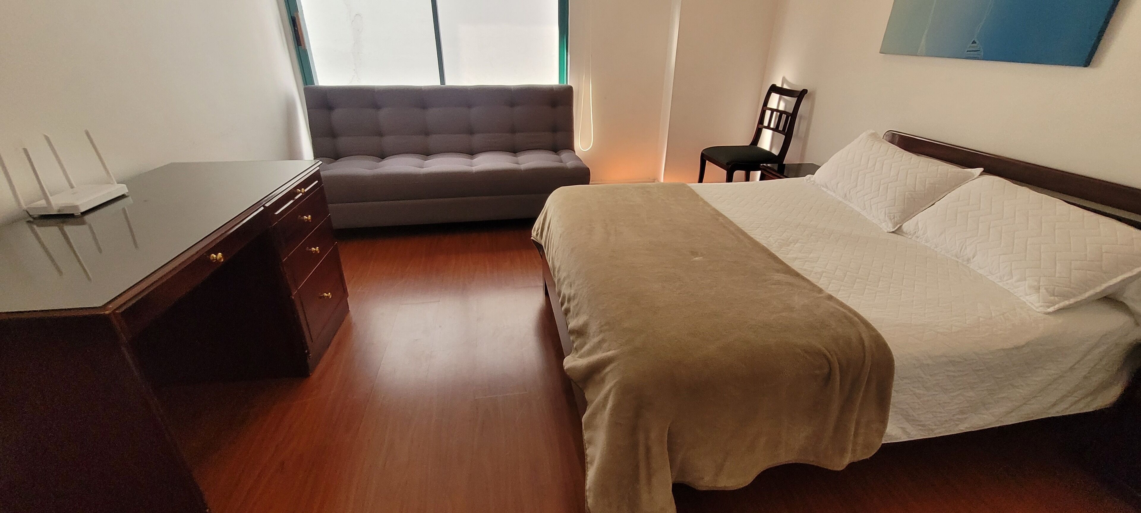 Ein Schlafzimmer mit einem Bett, einem Schlafsofa, einem Schreibtisch und einem Stuhl.