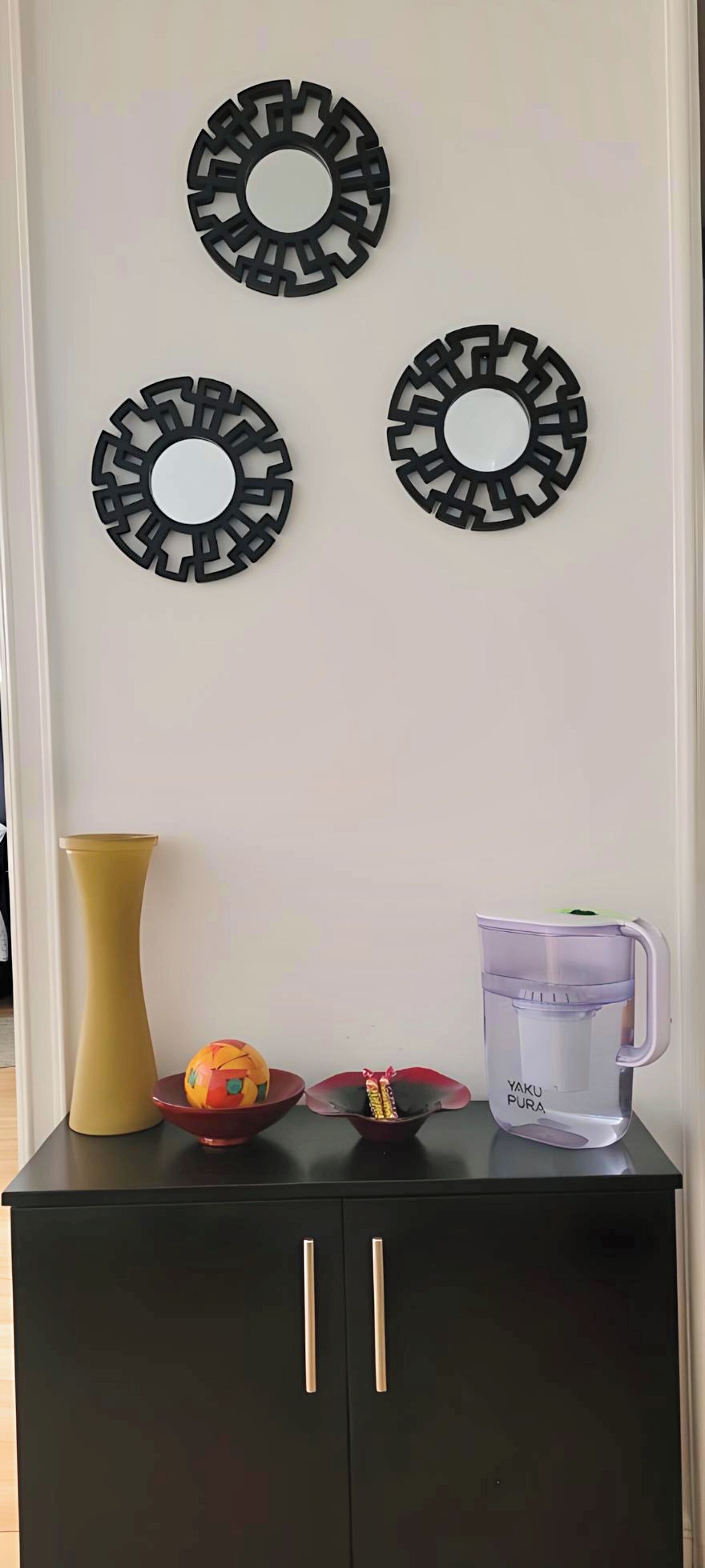 Un meuble noir avec deux tiroirs et un vase posé sur le dessus.