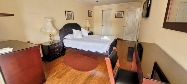 A bedroom with a bed, bedside tables, a desk, and a chair. - Fontana Suites (Quito)
