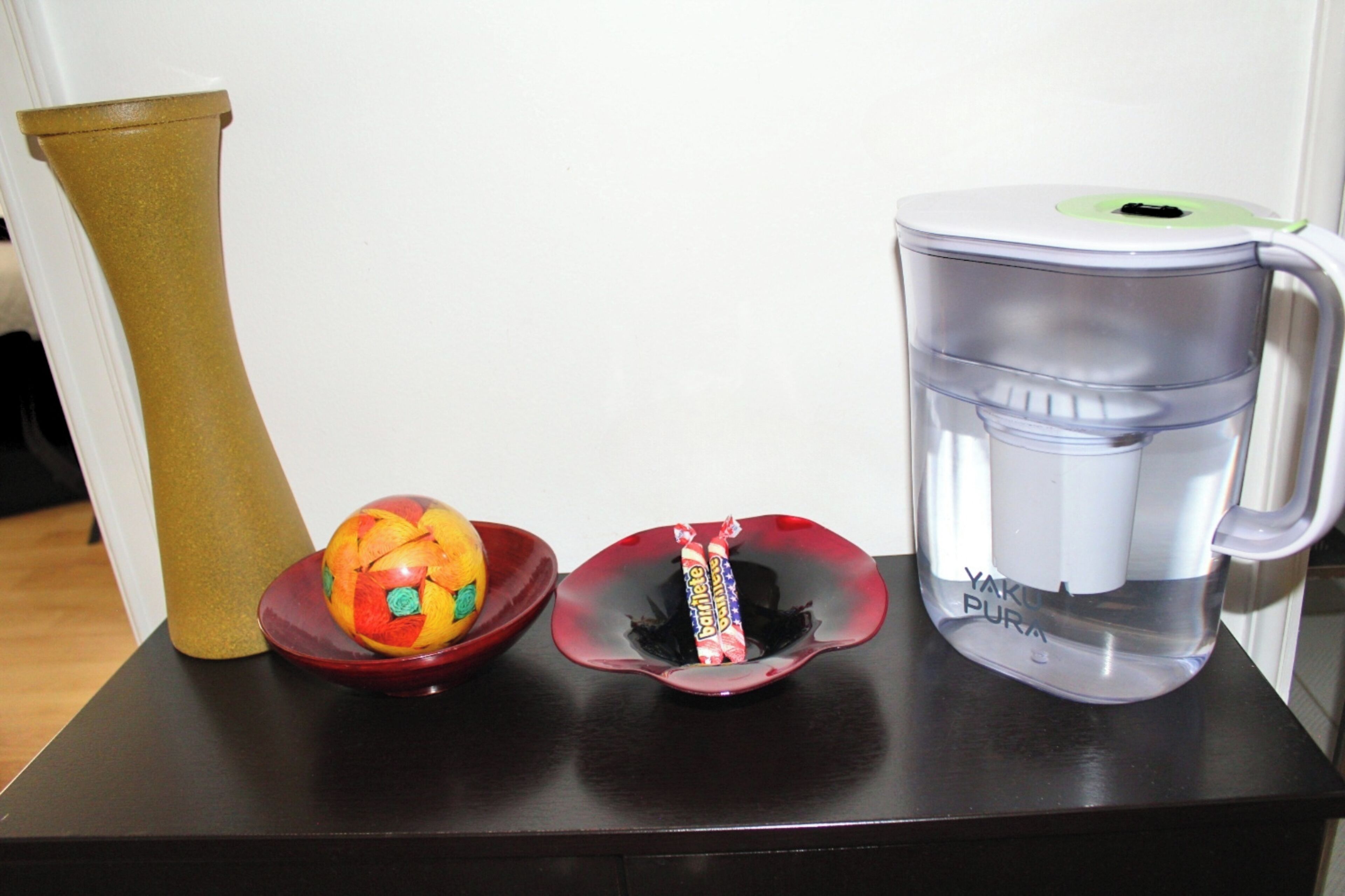 A coffee maker, a vase, and a fruit bowl on a table.