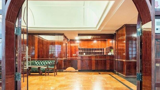 A lobby with a reception desk, a green sofa, and a marble floor. - Fontana Suites (Quito)