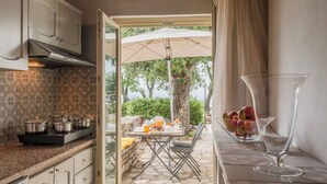 Een keuken met een zichtbare eetruimte door een open deur, met een ontbijttafel gedekt, inclusief fruit en een glas.