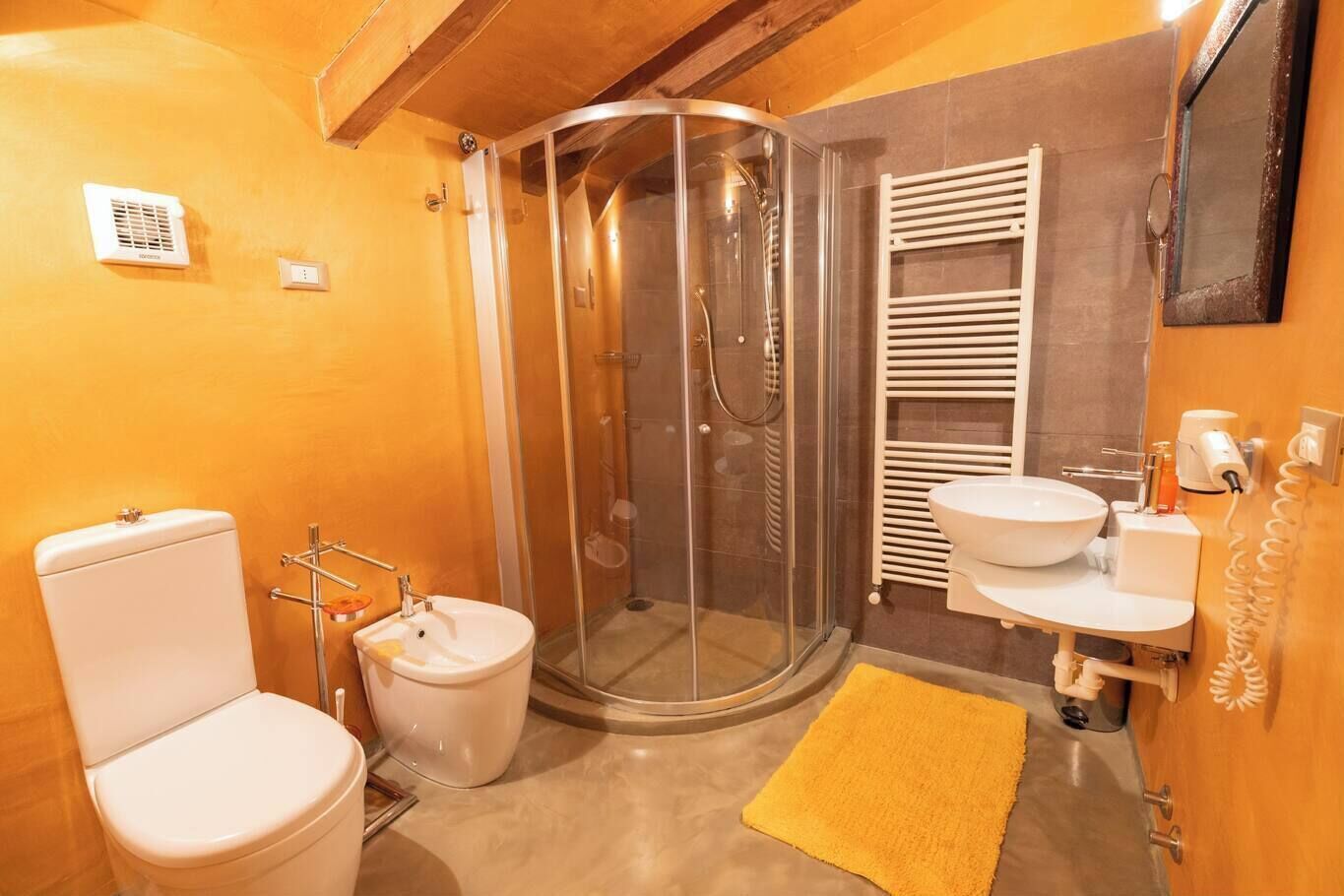 A bathroom with a toilet, sink, shower, and towel rack.