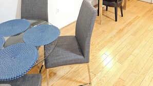 A dining area with a wooden table, grey upholstered chairs, and a colorful abstract painting on the wall.