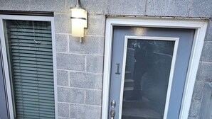 A gray stone building with a gray door and a window with blinds.