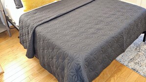 A bed with a dark quilted bedspread, two pillows, and a headboard.