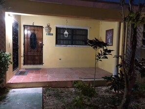 A charming entrance with a black gate, white window, and lantern, set against a warm-toned wall.