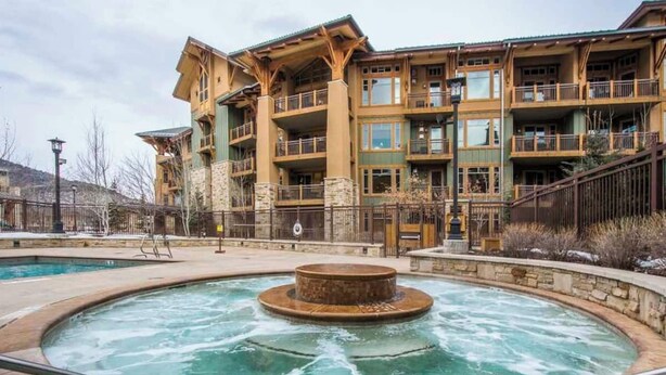 A multi-story hotel with balconies, a central courtyard with a hot tub, and a pool area.