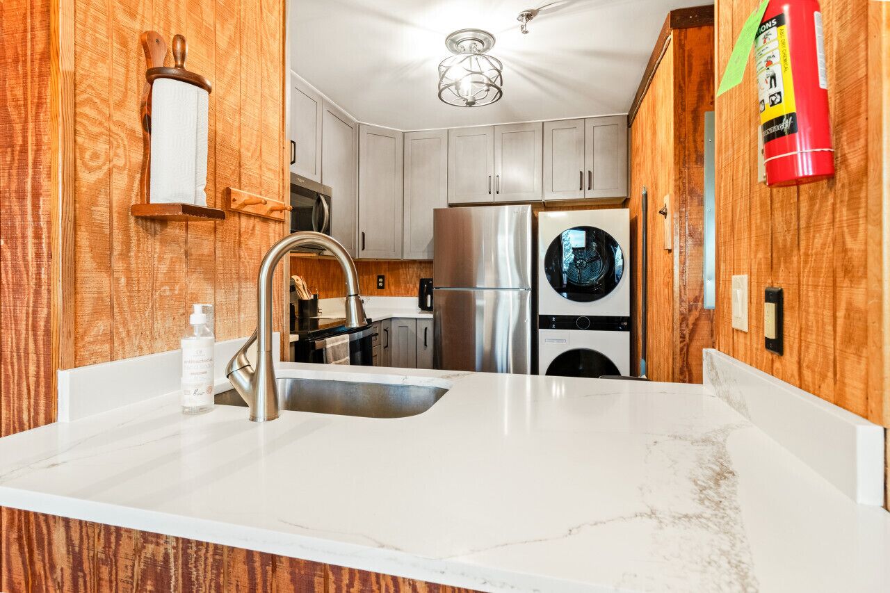 A modern kitchen with wooden cabinetry, stainless steel appliances, and a marble countertop.
