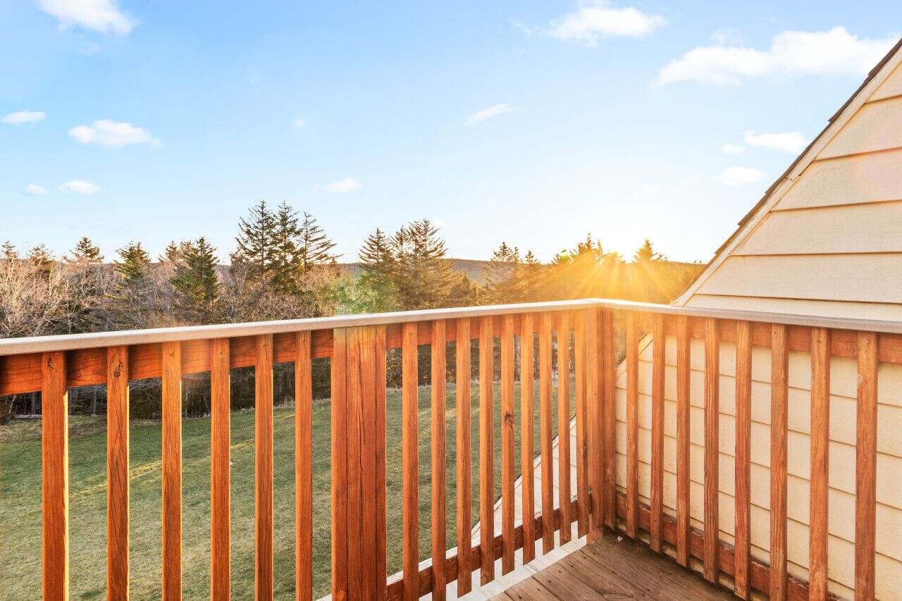 Une terrasse en bois offrant une vue sur une pelouse et des arbres.