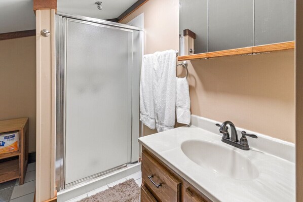 A bathroom with a shower, a sink, and a mirror.
