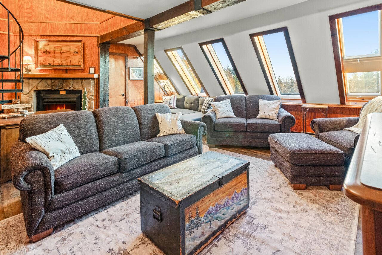 Un salon chaleureux avec une cheminée, plusieurs canapés et une grande armoire en bois.