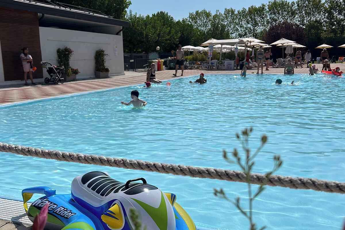 En swimmingpool med mennesker i vandet, en sikkerhedssnor og en oppustelig 'Wave Rider'.